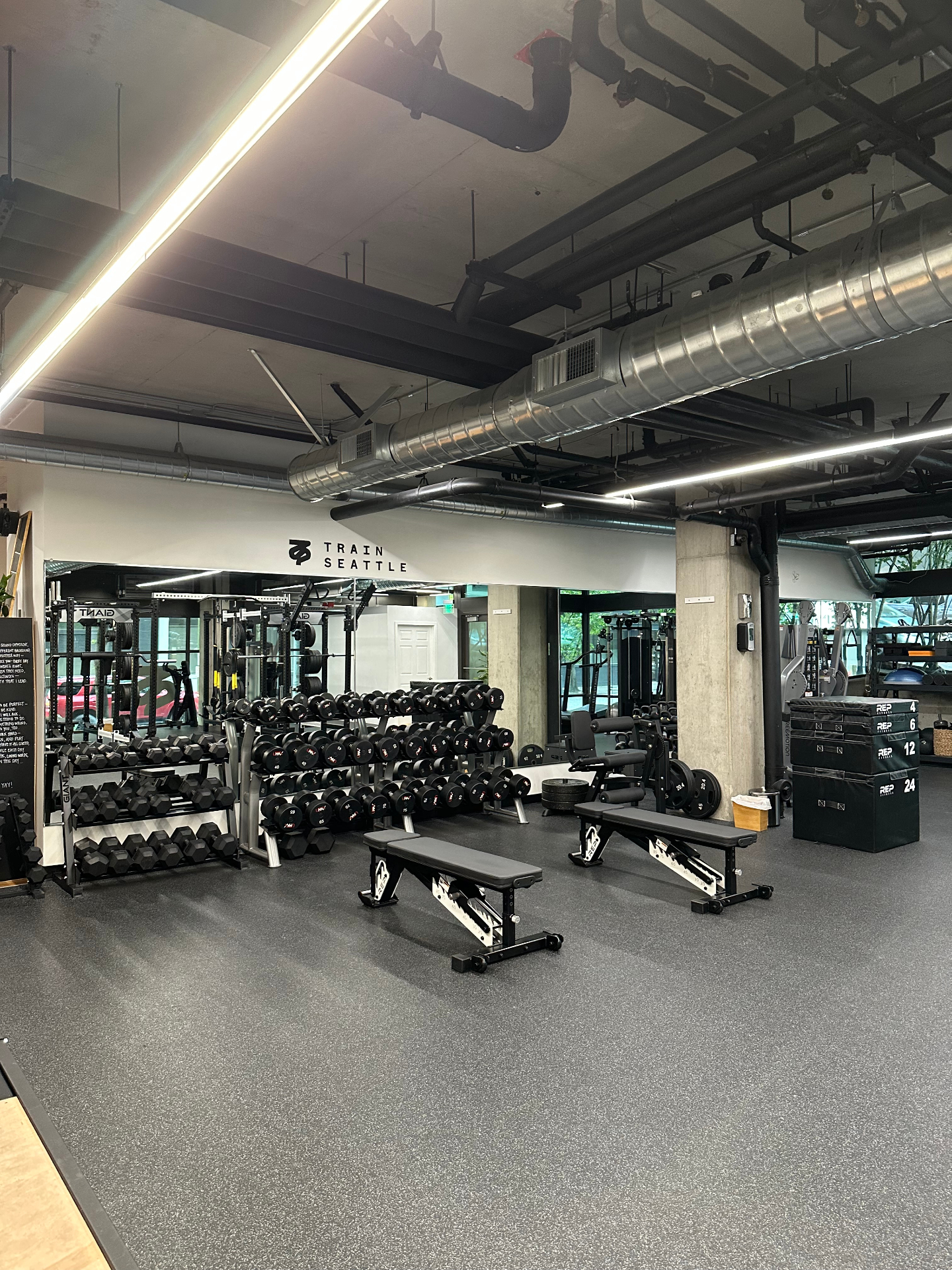 Wide view of the gym floor with dumbbells, benches, and plyo boxes